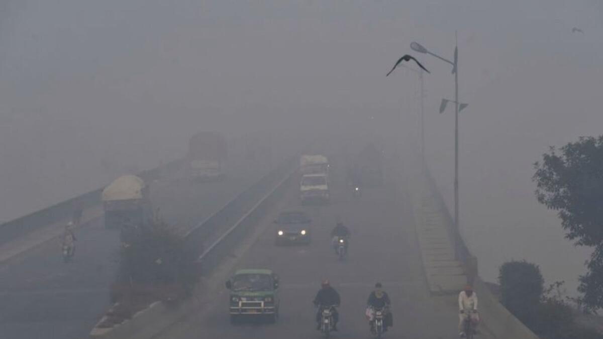 Commuters drive their vehicles amid heavy smog conditions in Lahore on November 21, 2019.