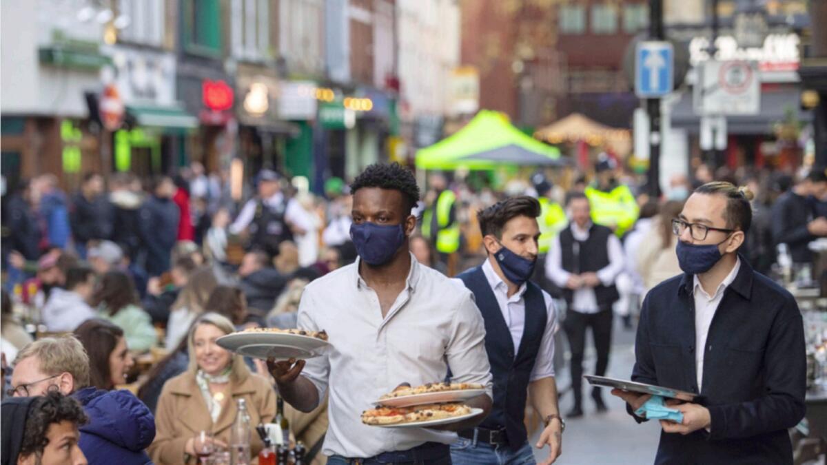 Waiters serve people eating and drinking at outside tables in Soho, central London, following easing of lockdown coronavirus restrictions in April. — AP