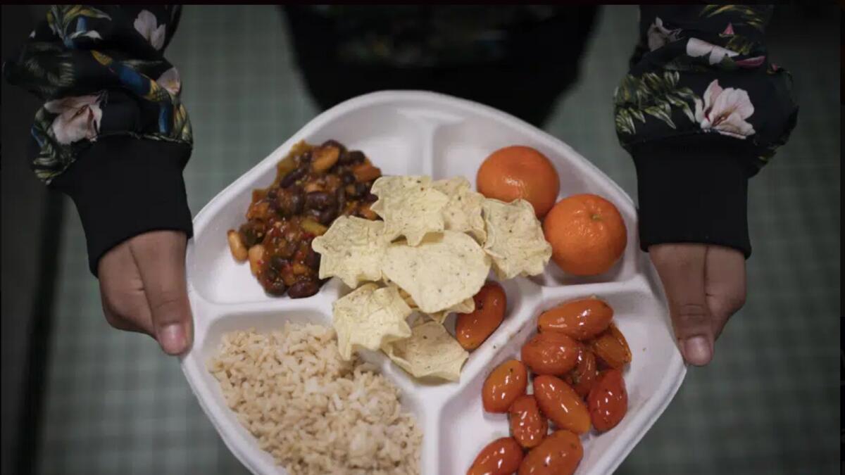 A seventh grader carries her plate which consists of three bean chili, rice, mandarins and cherry tomatoes and baked chips during her lunch break at a local public school in the Brooklyn borough of New York. — AP