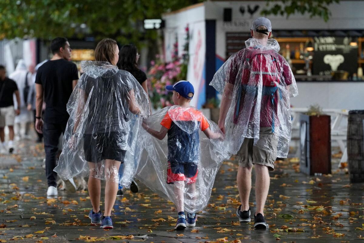 Members of the public wearing raincoats, walk during a downpour of rain, in London, Britain, August 17, 2022.  — Reuters