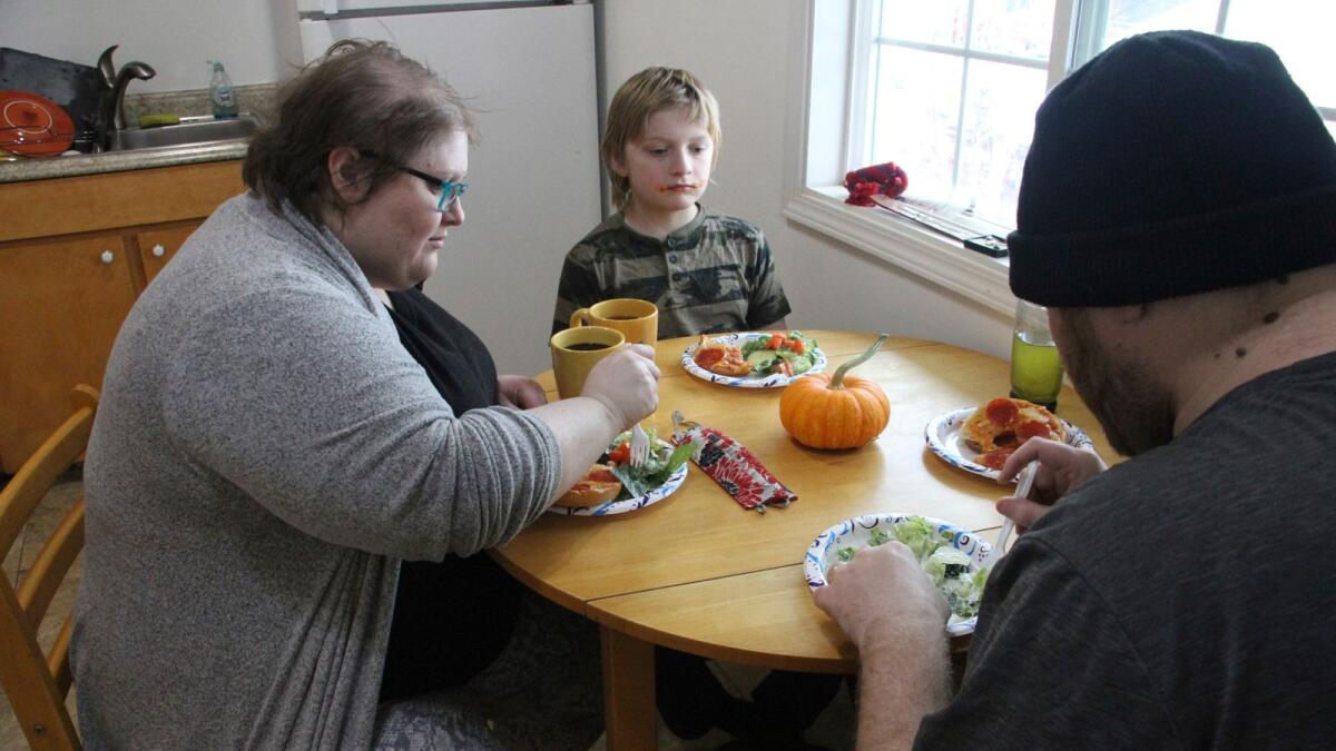 Airis Messick, left, and Brian Messick, right, eat lunch with this 9-year-old son, Jayden, at their apartment in Anchorage, Alaska, on Nov. 11, 2020. Messick and her husband have had to turn to food banks after both lost their jobs in the economic downturn caused by the coronavirus pandemic.