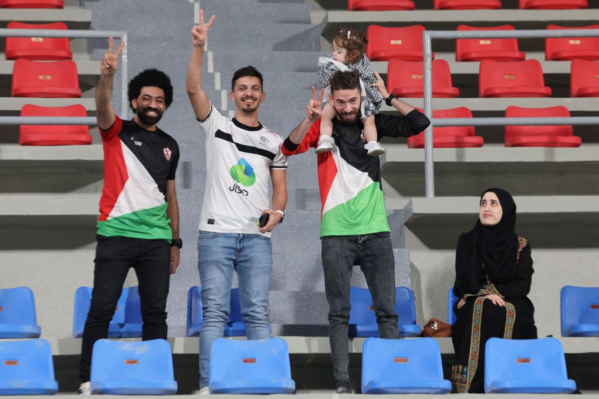 Fans wearing the colors of the Palestinian flag pose for a picture during the match. _ AFP