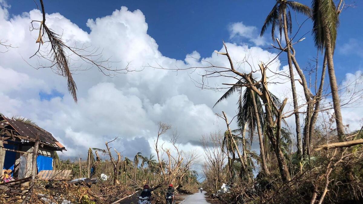 Motorists speeds past fallen coconut trees at the height of Super Typhoon Rai along a highway in Del Carmen town, Siargao island on December 20, 2021, days after Super Typhoon Rai hit the province. (Photo: AFP)