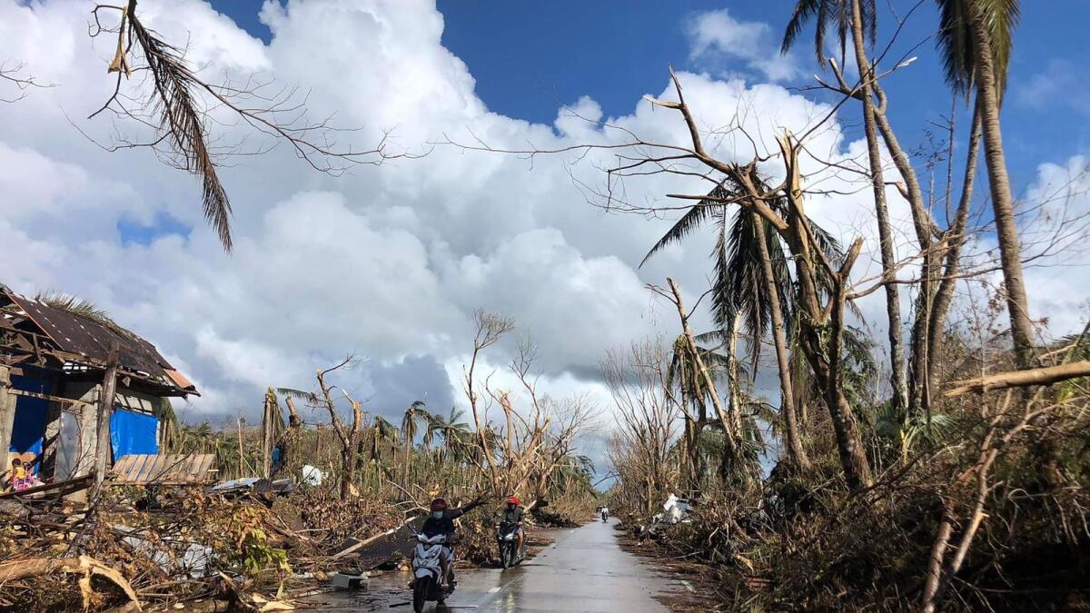 Motorists speeds past fallen coconut trees at the height of Super Typhoon Rai along a highway in Del Carmen town, Siargao island on December 20, 2021, days after Super Typhoon Rai hit the province. (Photo: AFP)