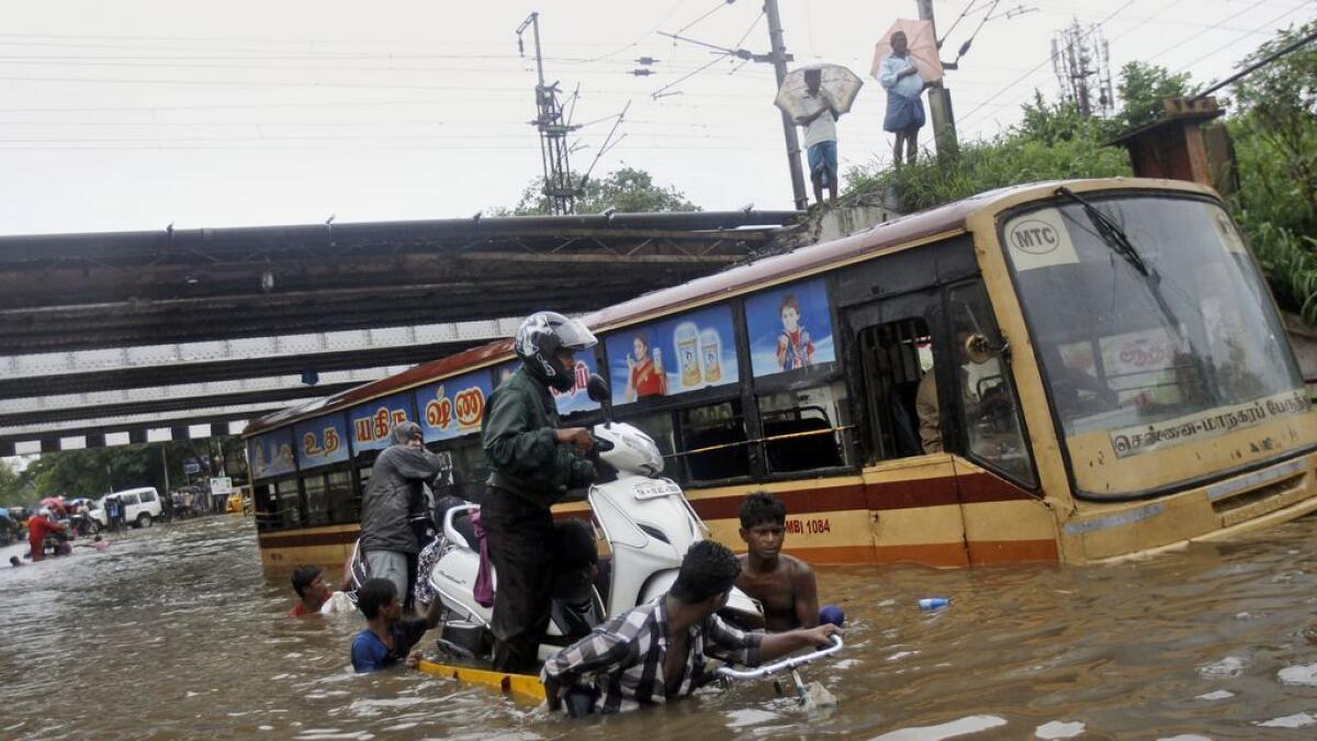 Indians help a man carry his two-wheeler on a cycle cart as they wade through a waterlogged subway in Chennai, India.