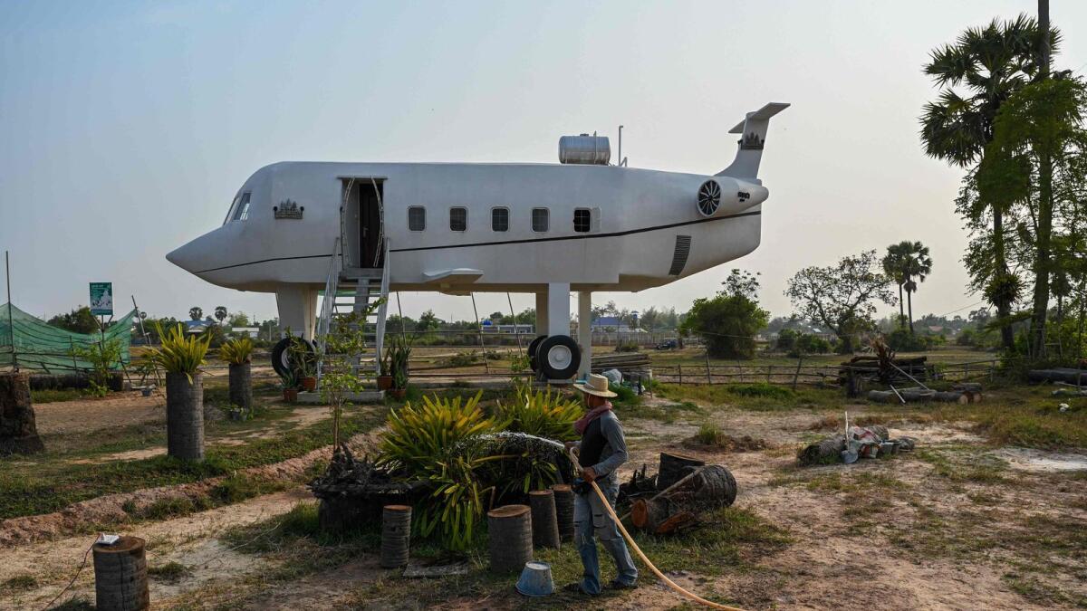 Chrach Peou spraying water in a garden in front of his house that is shaped like an aeroplane in Siem Reap province. A Cambodian airplane fanatic has built his house shaped like a private jet -- despite never having been up in the air himself. - AFP
