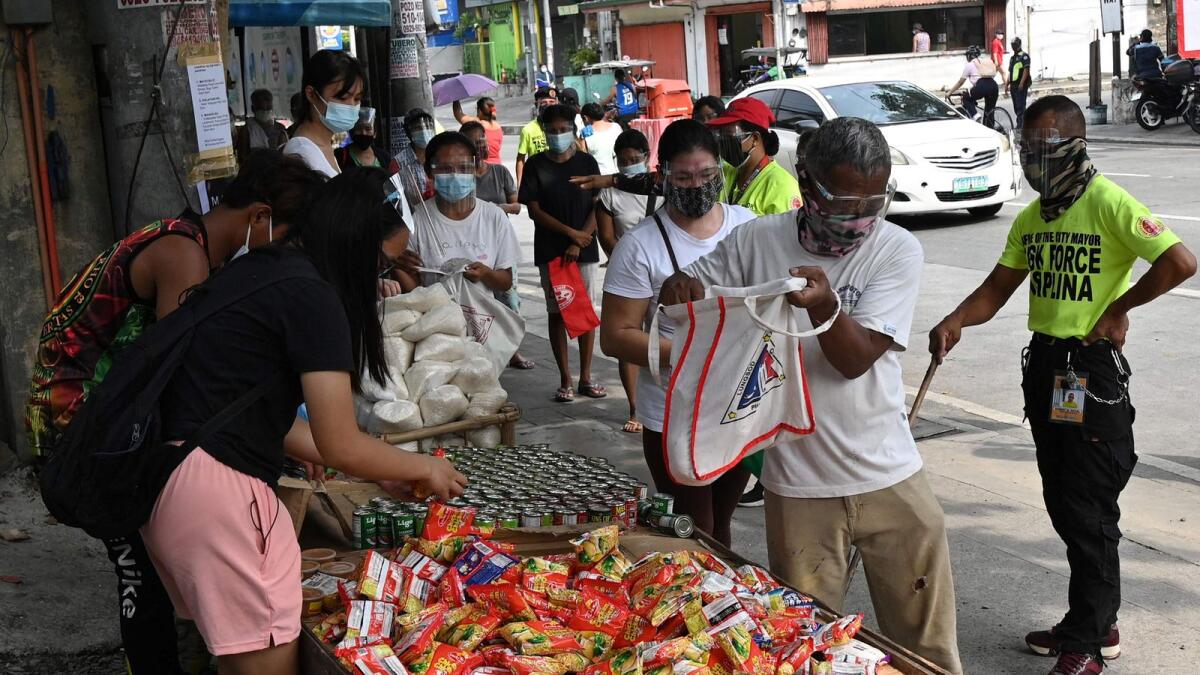 Residents collecting free food packets from a food bank called a 'community pantry', run by volunteers, along a road in Quezon City in suburban Manila.