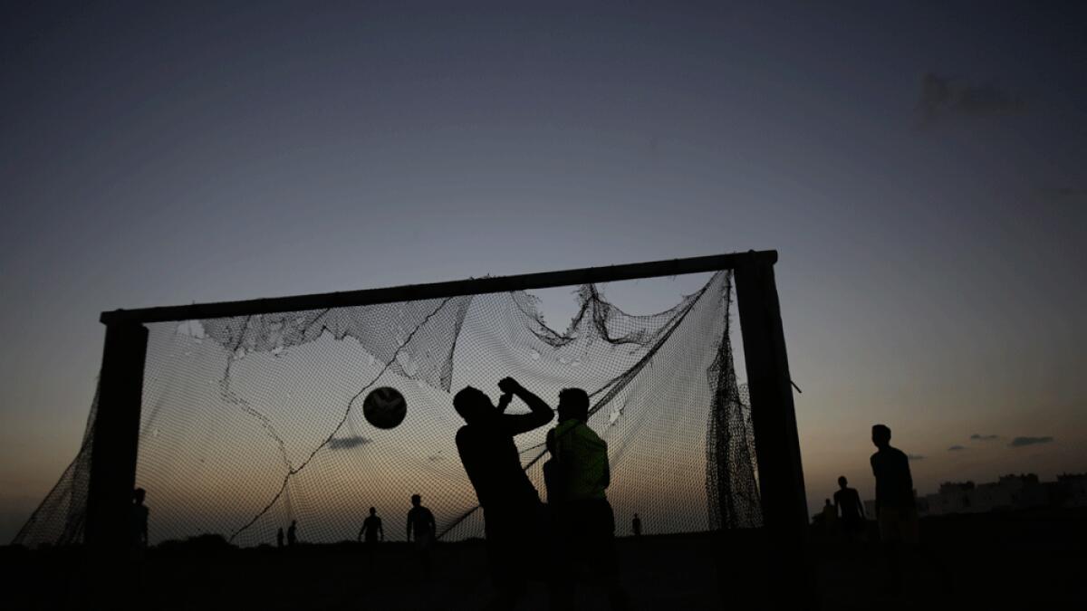Bahraini youths play soccer on a village field as the sun sets in Malkiya, Bahrain.