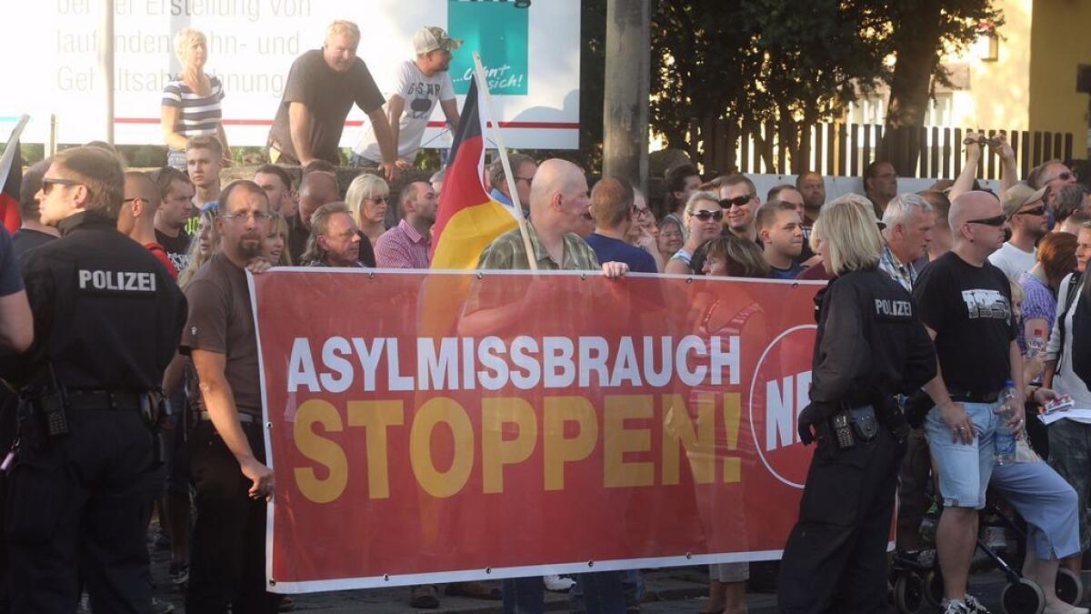 Right-wing demonstrators hold a sign 'stop misuse of asylum' as they protest against a tent camp for refugees in Dresden, eastern Germany.