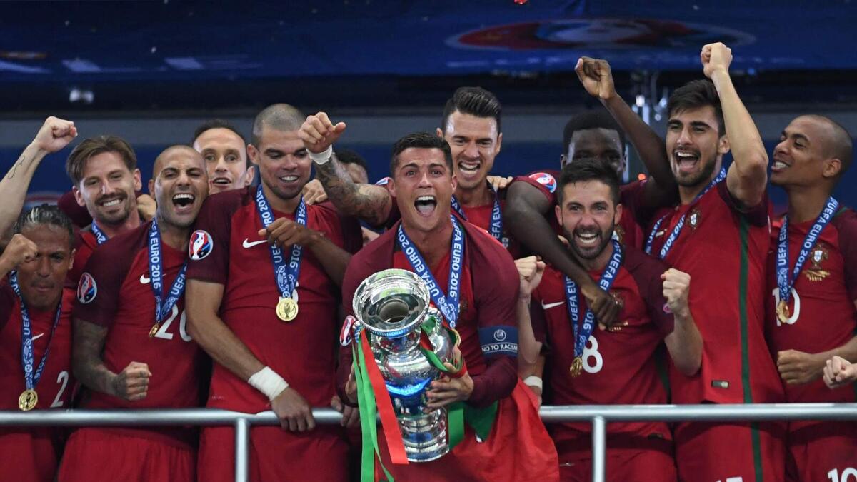 Portugal’s Cristiano Ronaldo (centre) lifts the trophy as he celebrates with teammates after winning the Euro final against France at the Stade de France. — AFP