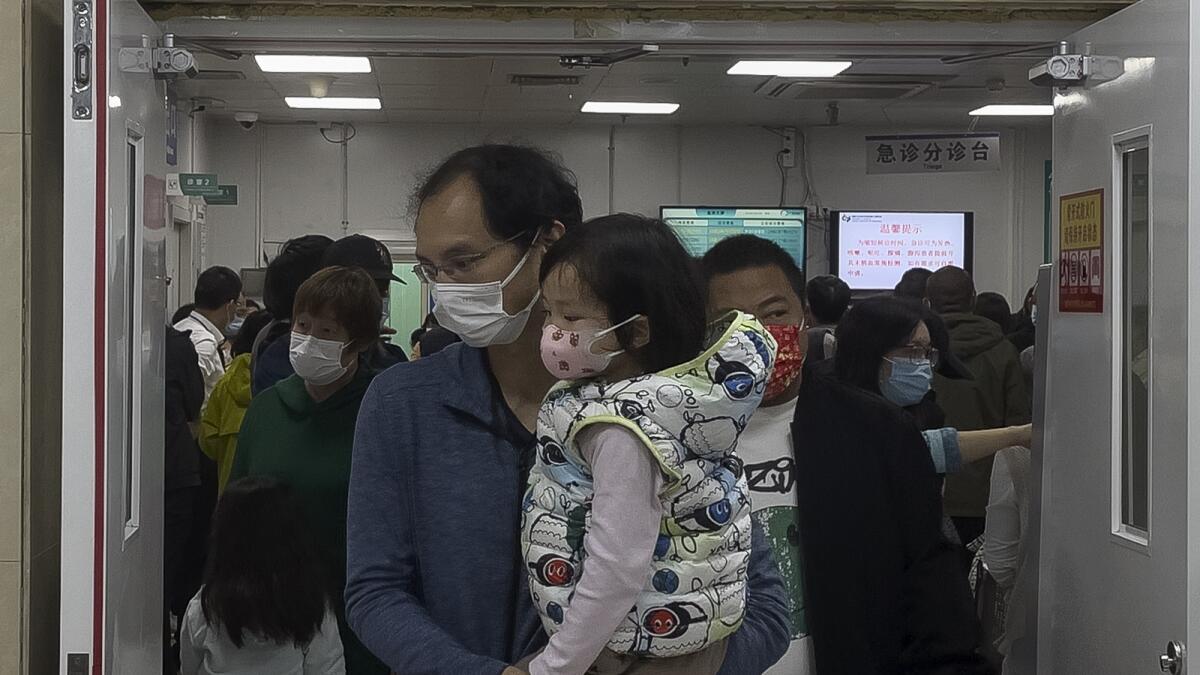 A man carrying a child walks out from a crowded holding room of a children's hospital in Beijing. — AP
