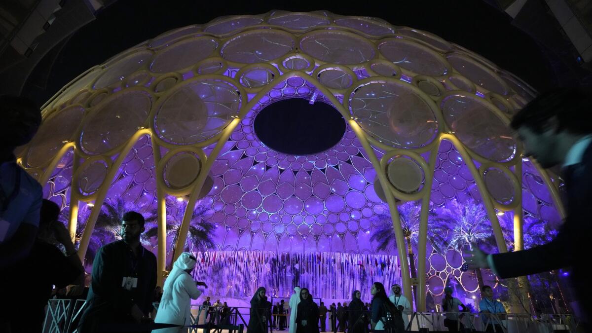 People walk near a lit up Al Wasl Dome at Expo City. - AP