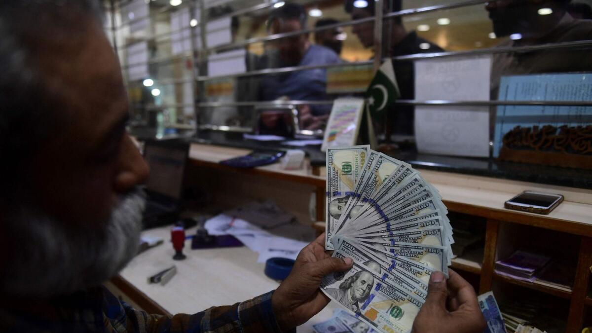 A dealer counts US dollars at a money exchange market in Karachi. The credit facility will boost Pakistan’s forex reserves by about 20 per cent. — AFP