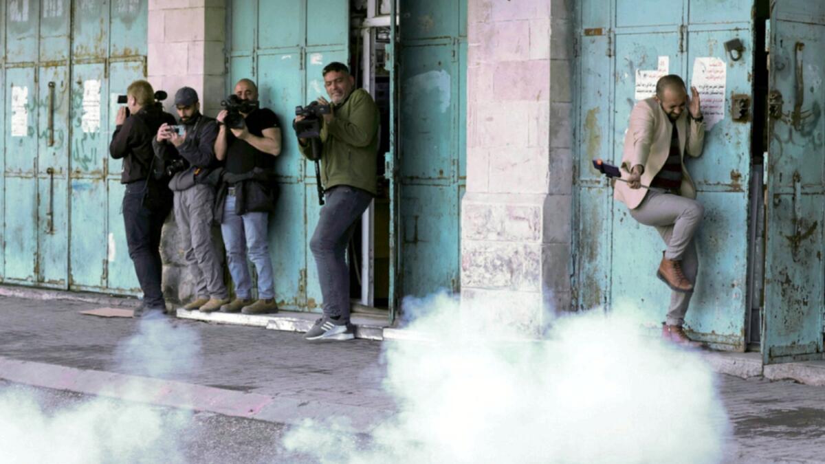 Journalists react to a sound grenade as they cover clashes between Palestinian protesters and Israeli security forces in the West Bank town of Hebron. — AFP