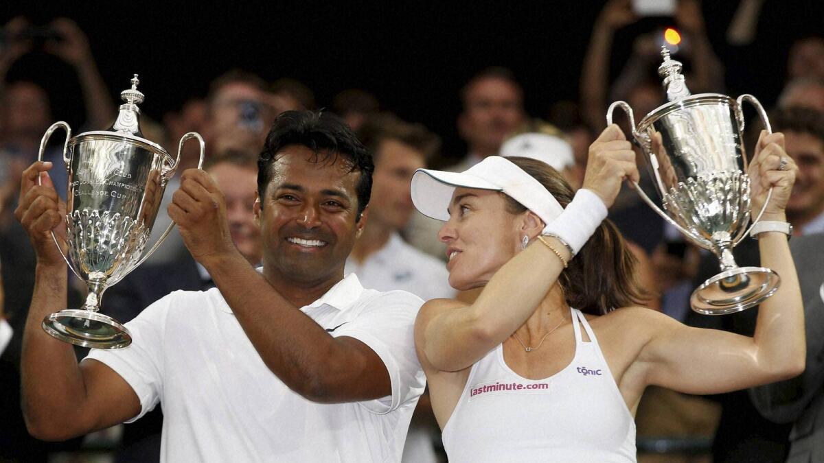 Leander Paes of India and Martina Hingis of Switzerland hold up the trophies after winning the mixed doubles title. — AP