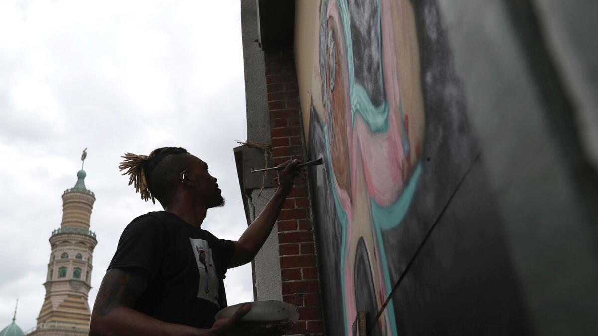 Fitz Young paints a mural on a business on Massachusetts Avenue, on Monday, June 8, 2020.  Black artists are painting murals on businesses that have been boarded up, after days of demonstrations.