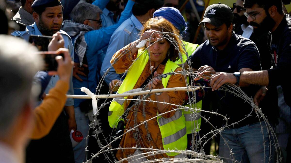 An activist of Aurat March removes barbed wires as police try to stop them during a rally to mark the International Women's Day in Islamabad on Wednesday. — AFP