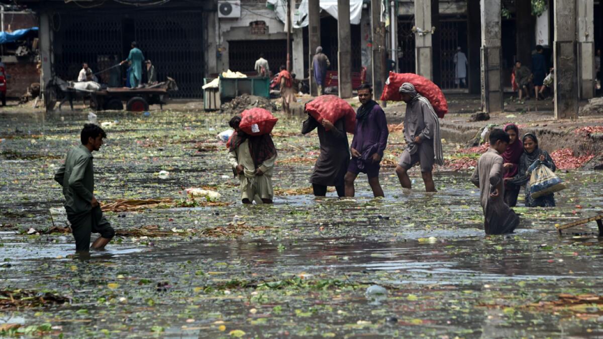 Labourers wade through a flooded fruit and vegetable market after heavy monsoon rains in Lahore, Pakistan. Photo: AFP