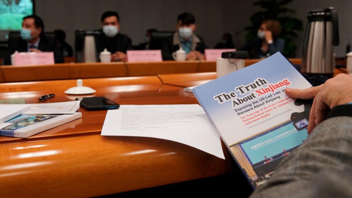 A journalist flips through a book titled The truth about Xinjiang during a press conference in Beijing.