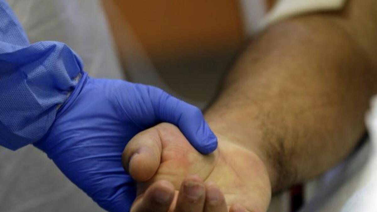A member of the medical staff holds the hand of a patient suffering from the coronavirus at the ICU of the General University Hospital in Prague, Czech Republic.