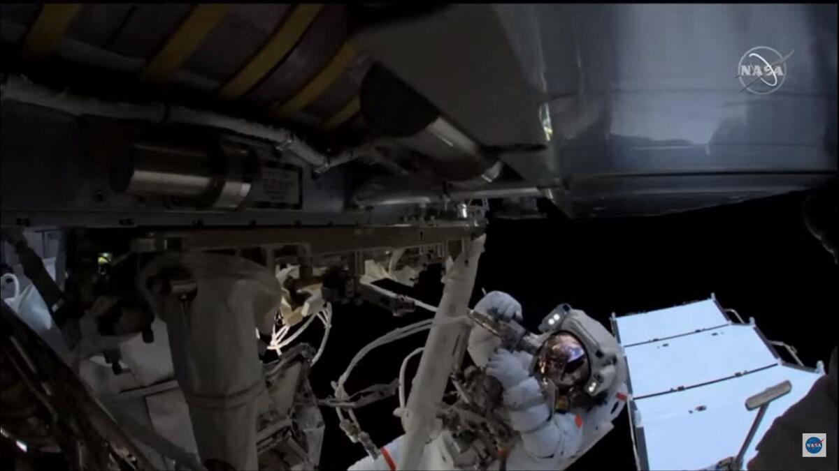 European Space Agency astronaut Thomas Pesquet (R) holding a space drill during spacewalk to complete work on the IROSA Solar Array.