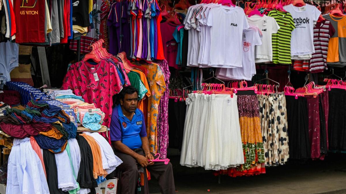 A garment store vendor waits for customers at a market in Colombo. The global outlook is helping drive the dollar higher as US yields look attractive and investors think other economies look too fragile to sustain rates as high as those contemplated in the US. — AFP