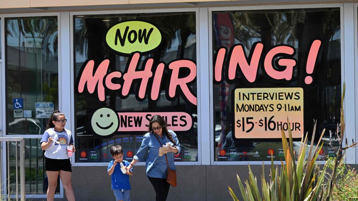 A family walks past a ‘Hiring’ sign at a McDonald’s restaurant in Garden Grove, California. — AFP file