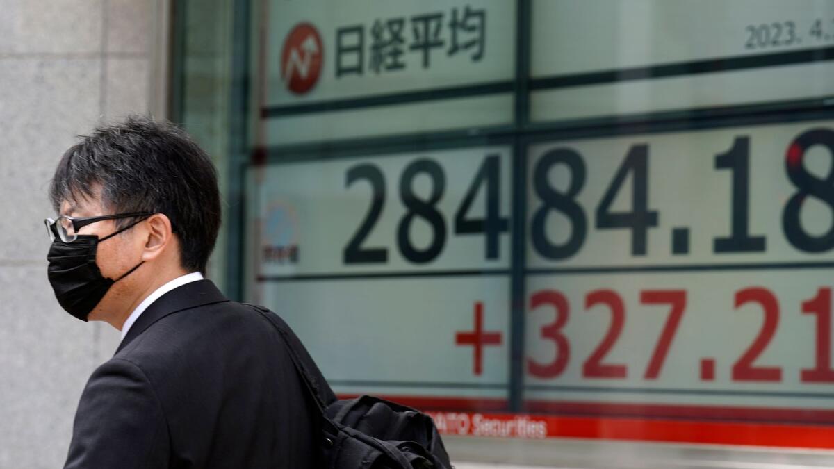 A person walks past in front of an electronic stock board showing Japan's Nikkei 225 index at a securities firm on Friday in Tokyo. Asian stock markets followed Wall Street higher on Friday after US inflation eased in March and China reported unexpectedly strong exports. - AP