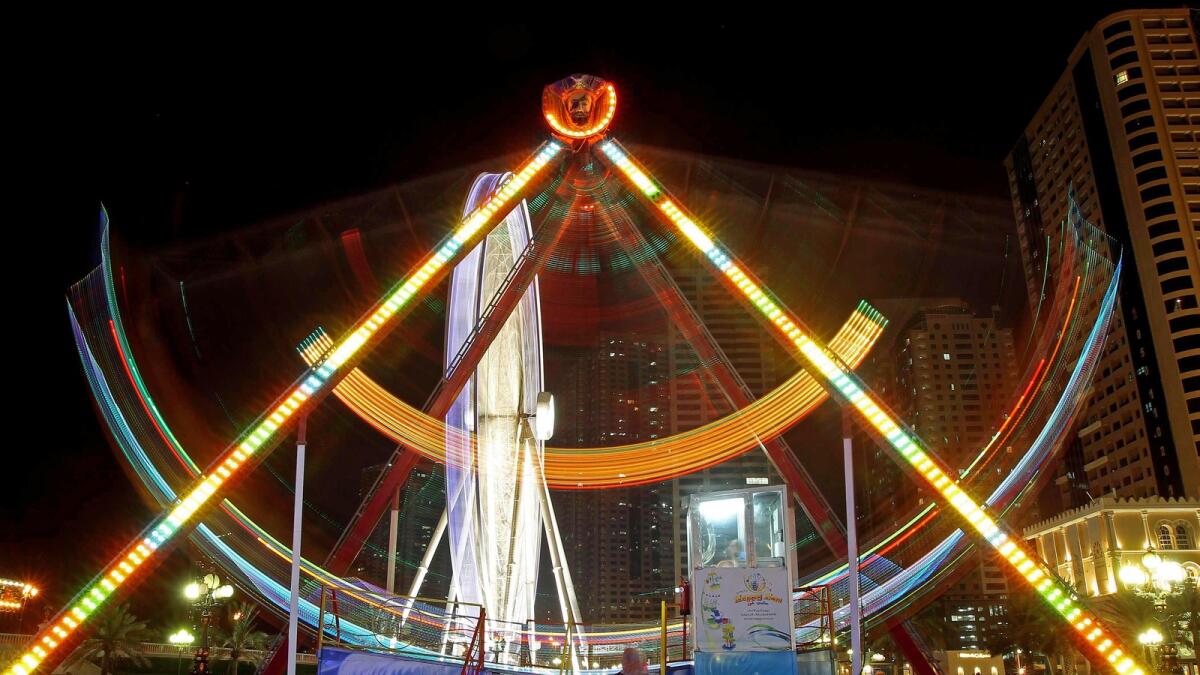 A lady is standing in front of the giant swing while her kids are having a ride at the Al Qasba in Sharjah.-Photo by M.Sajjad/ Khaleej Times