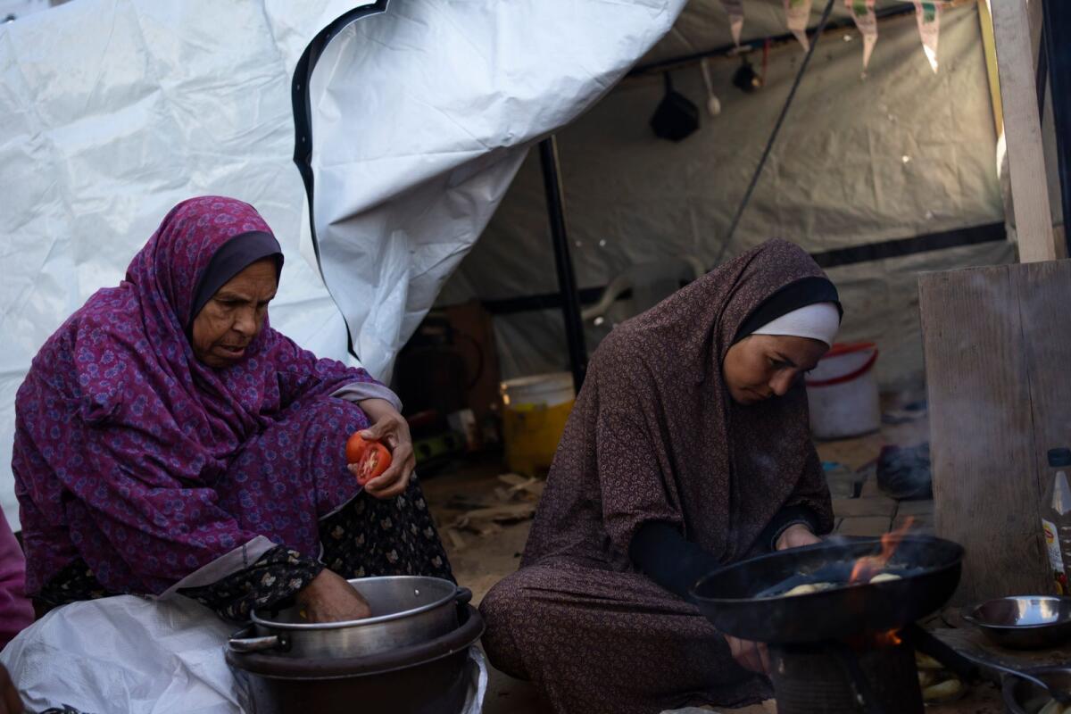 Randa Baker, Right, who was displaced by the Israeli bombardment of the Gaza Strip, prepares the Iftar meal with her mother on the first day of Ramadan. — AP