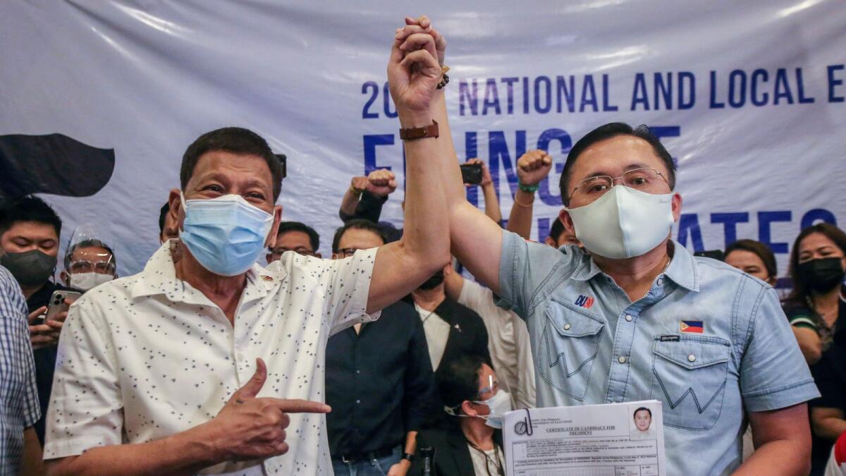 Philippine President Rodrigo Duterte (L) raises the hand of senator Christopher 'Bong' Go after he filed his candidacy for president in the 2022 elections before the November 15 deadline at the Commission on Election in Manila on November 13, 2021. (Photo:AFP)