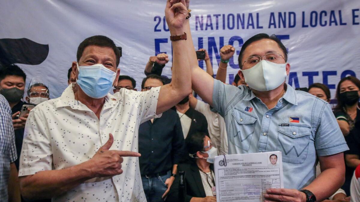 Philippine President Rodrigo Duterte (L) raises the hand of senator Christopher 'Bong' Go after he filed his candidacy for president in the 2022 elections before the November 15 deadline at the Commission on Election in Manila on November 13, 2021. (Photo:AFP)