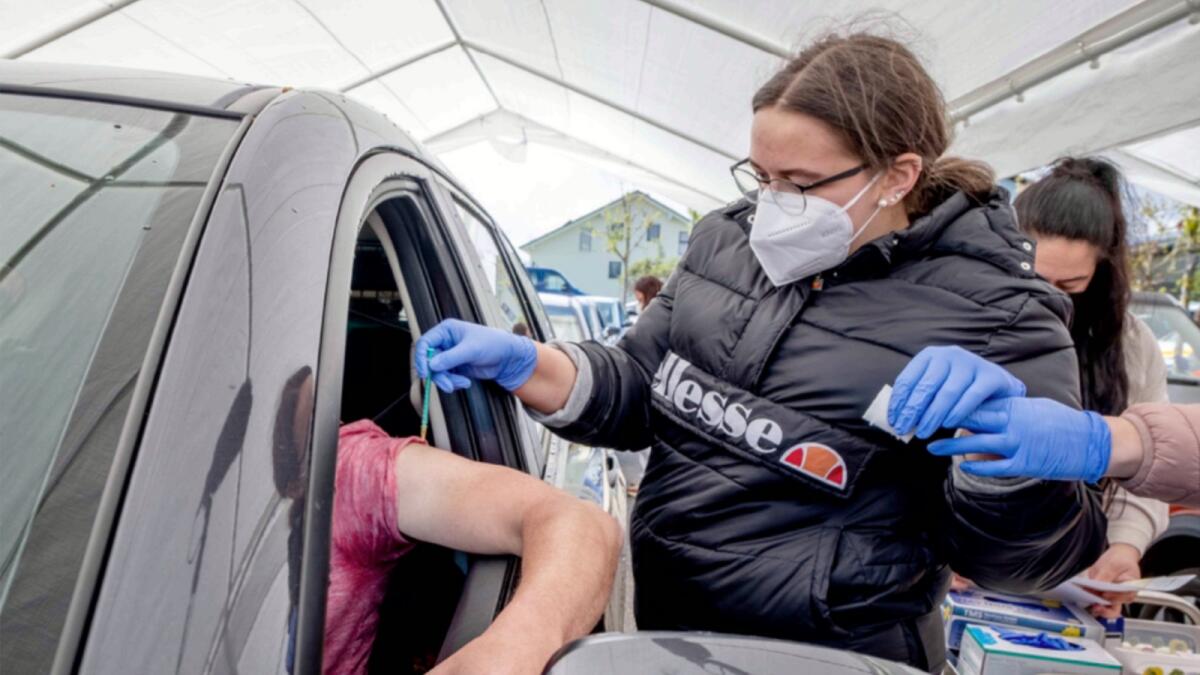 A man sits in his car as he is vaccinated with AstraZeneca in a tent on the parking lot of a supermarket in Germany. — AP