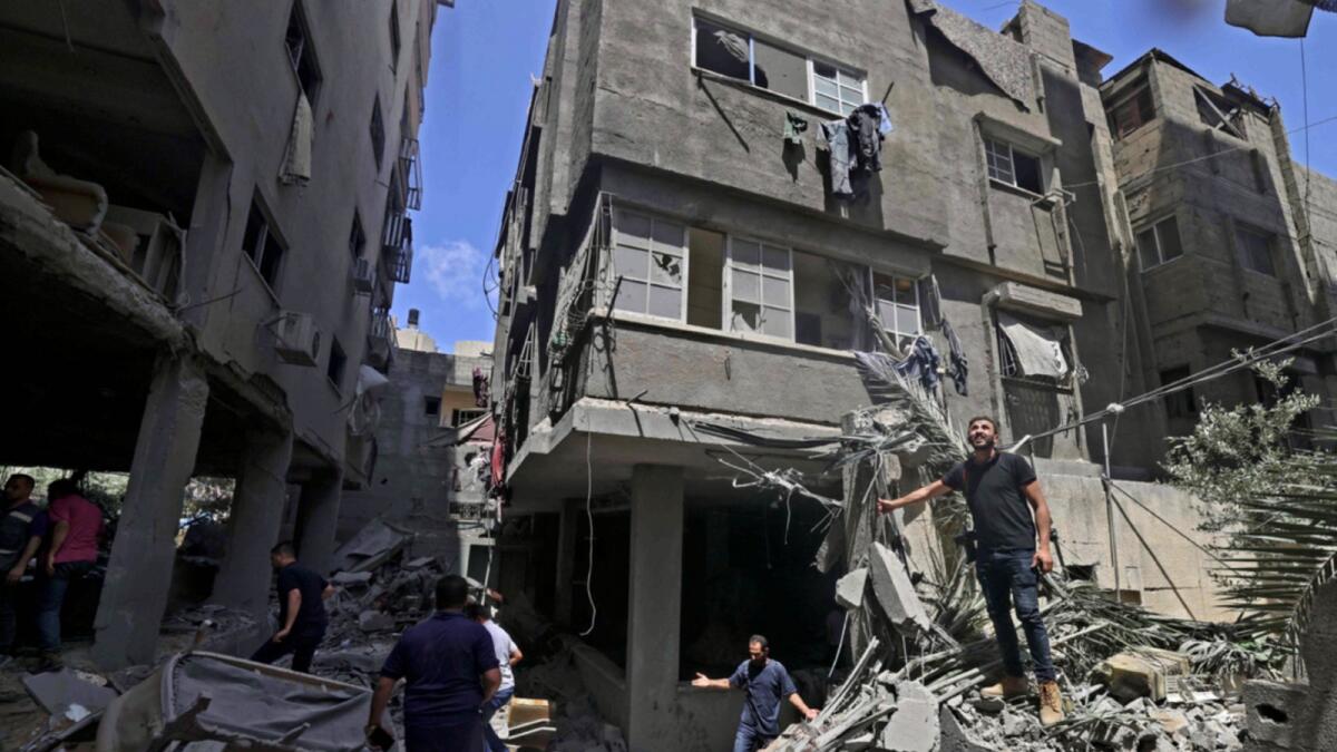 Palestinians inspect buildings damaged during Israeli air strikes in Gaza City. — AFP