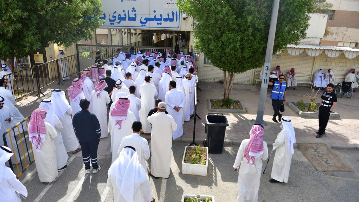 People stand in line to cast their votes in National Assembly elections at a religious school in Sabahiya district, Kuwait, on Tuesday. — AP