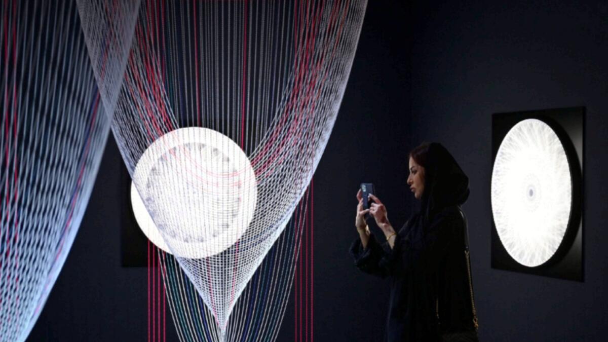 A visitor takes pictures of an artwork called ‘Lights and Gravity’ by Zilvinas Kempinas of USA.