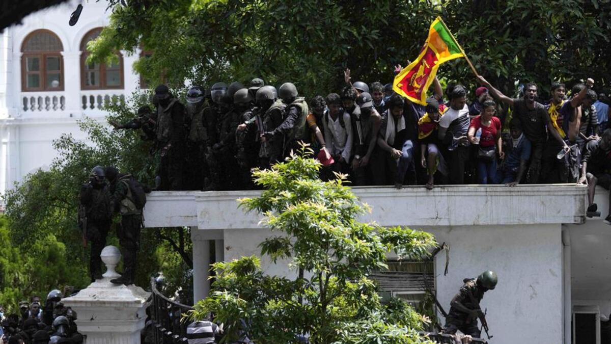 Protesters, one carrying national flag, storm the Sri Lankan Prime Minister's office, demanding he resign