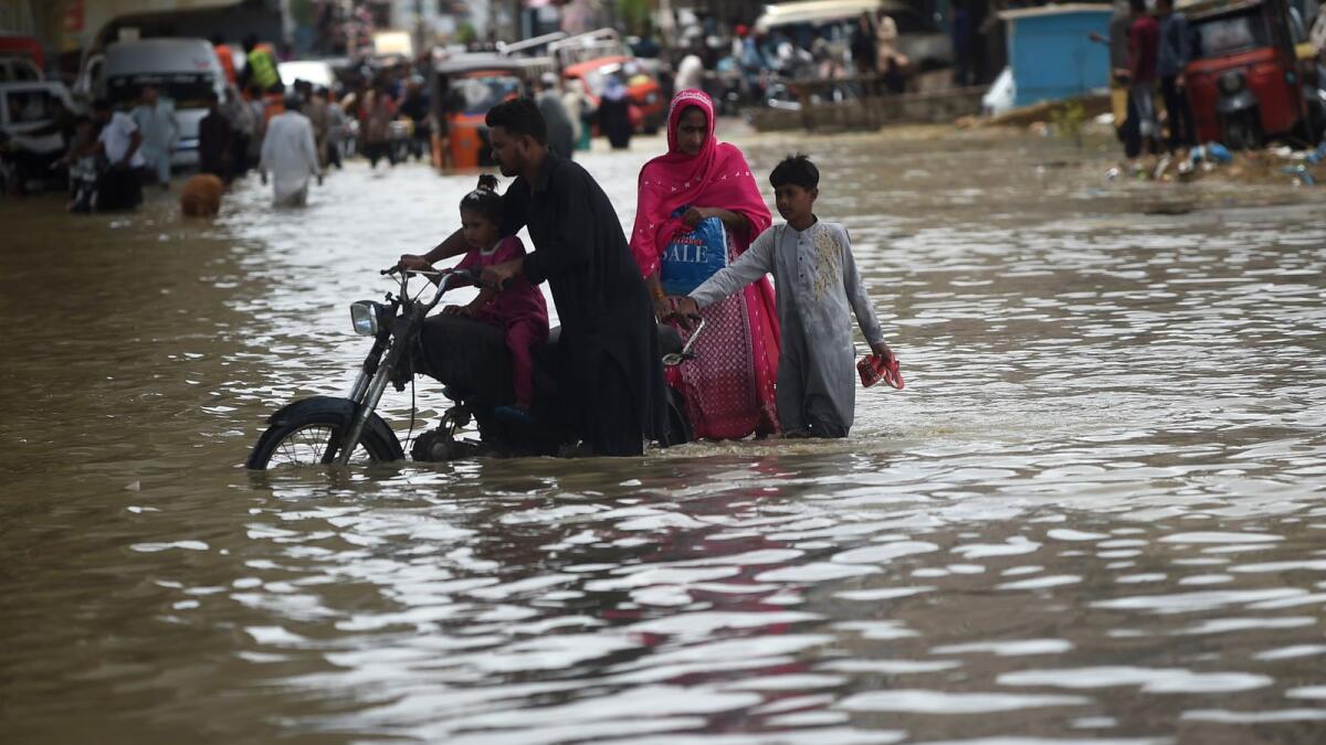 A family wades through a flooded street after a heavy rain shower in Karachi on July 11, 2022. Photo: AFP