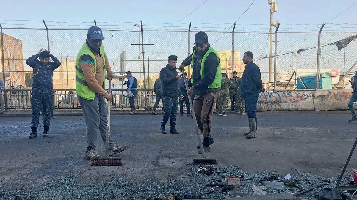 Municipality workers clean the scene of the double suicide bombing in Baghdad on Monday. — AP