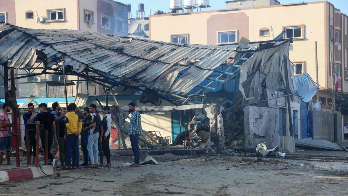 People gather next to a damaged UNRWA food aid warehouse and distribution center due to Israeli strikes in Tall al-Hawa neighbourhood in southern Gaza City on October 16, 2023. (Photo: AFP)