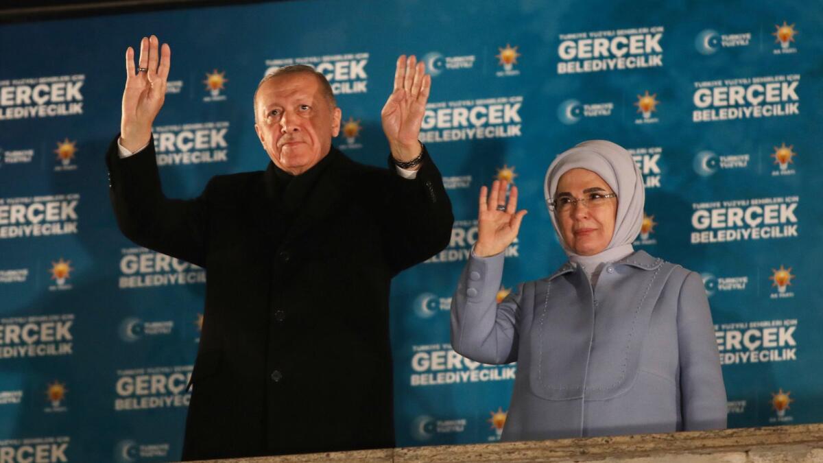 Turkish President and leader of the Justice and Development Party Recep Tayyip and his wife Emine Erdogan gesture to supporters at his party headquarters in Ankara early on Monday. — AP