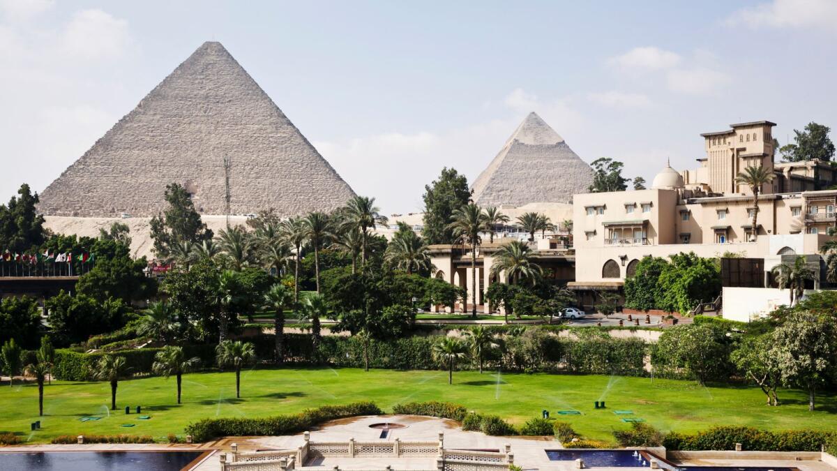 The ancient pyramids of Giza stand beyond the gardens of the Mena House hotel in Cairo. — File photo