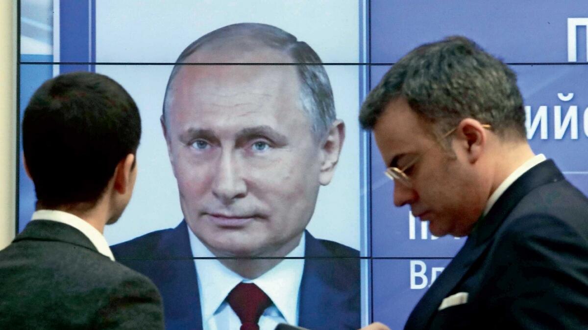 Men stand in front of a screen showing preliminary results of Russian President Vladimir Putin in the presidential election, at the headquarters of Russia’s Central Election Commission in Moscow, on Monday.  — Reuters