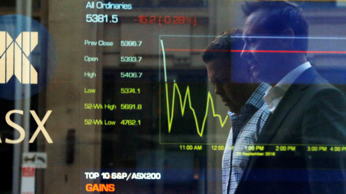 City workers walk past Australia's stock exchange index displayed on an electronic board in Sydney, September 20, 2016 a day after Australia's Security Exchange suffered a technical glitch which disrupted trading.   Reuters