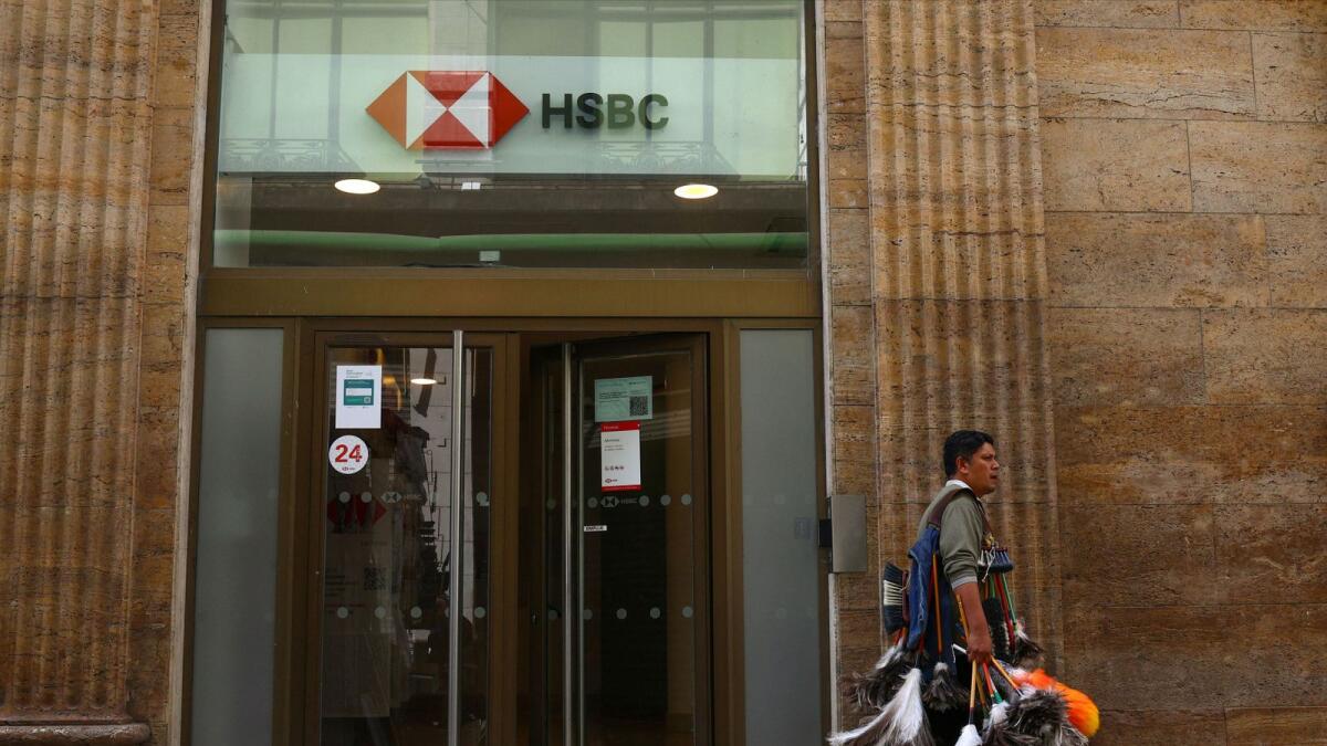 A feather duster seller walks past an HSBC branch in downtown Buenos Aires, as the bank is selling its business in the country. — Reuters