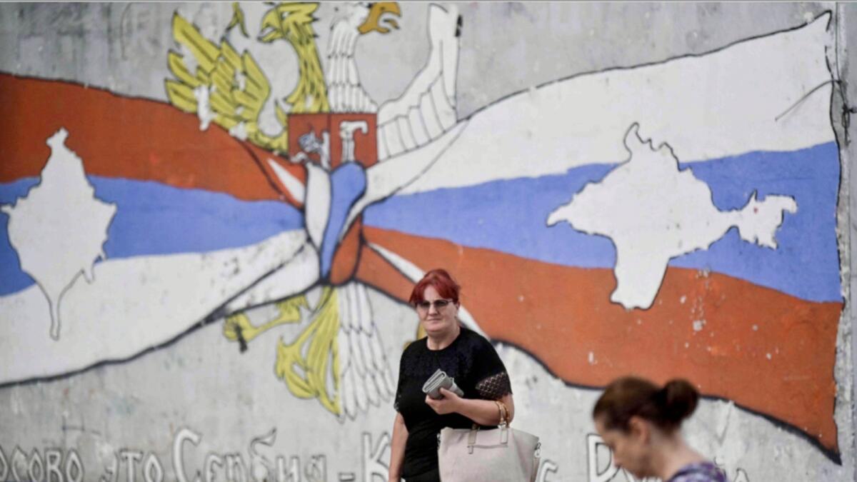 Kosovo Serbs walk next to a mural reading 'Kosovo is Serbia and Crimea is Russia' in the Serb majority north of Mitrovica. — AFP file