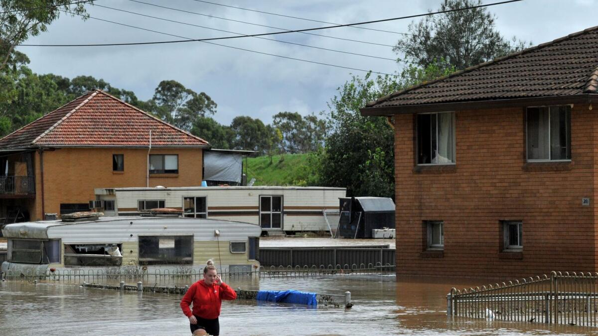 A resident fades through water in western Sydney on March 3, 2022, as the area faces its worst flooding after record rainfall caused its largest dam to overflow. Photo: AFP
