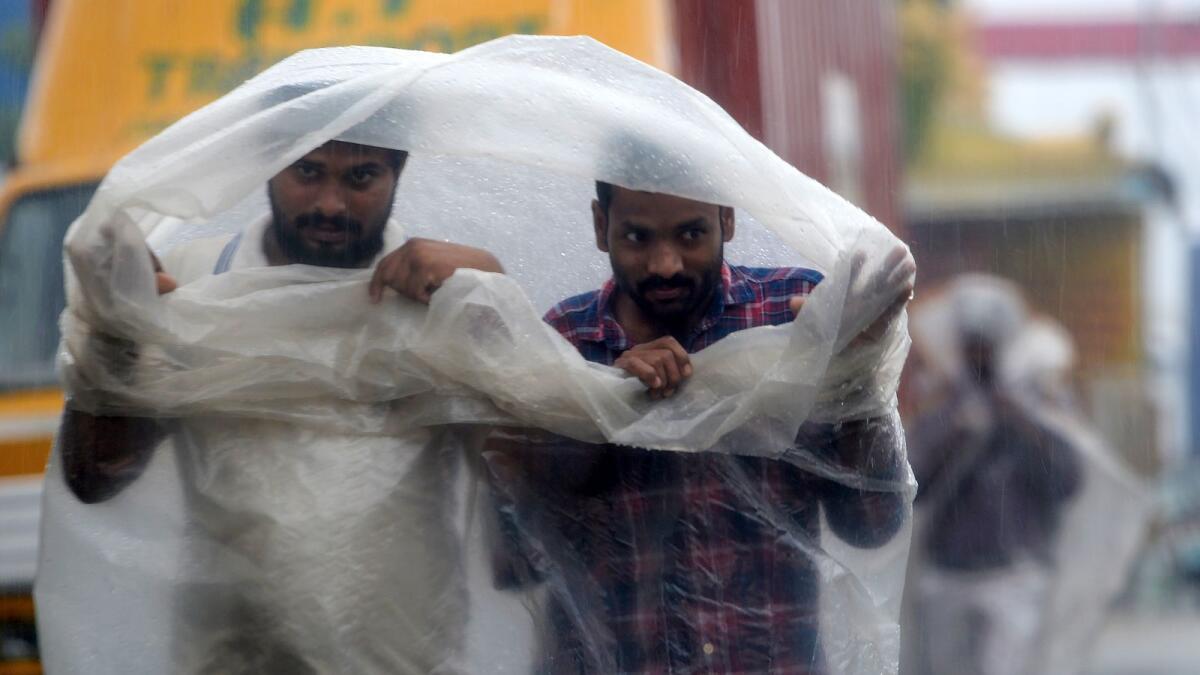 People use plastic sheets to cover from heavy rains in Chennai as cyclone Nivar approaches the southeastern coast of the country on November 25, 2020.