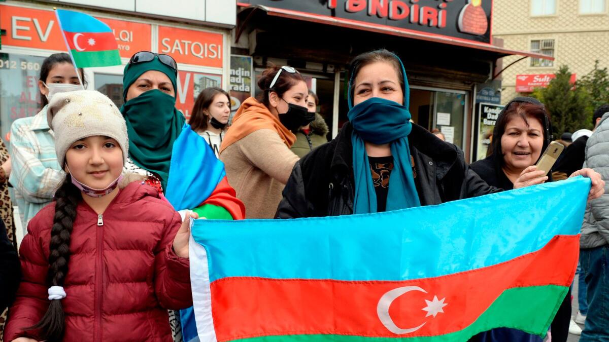 A woman holds an Azeri flag as people in the street celebrate the capture the town of Shusha in Baku during the ongoing military conflict between Armenia and Azerbaijan over the breakaway region of Nagorno-Karabakh.