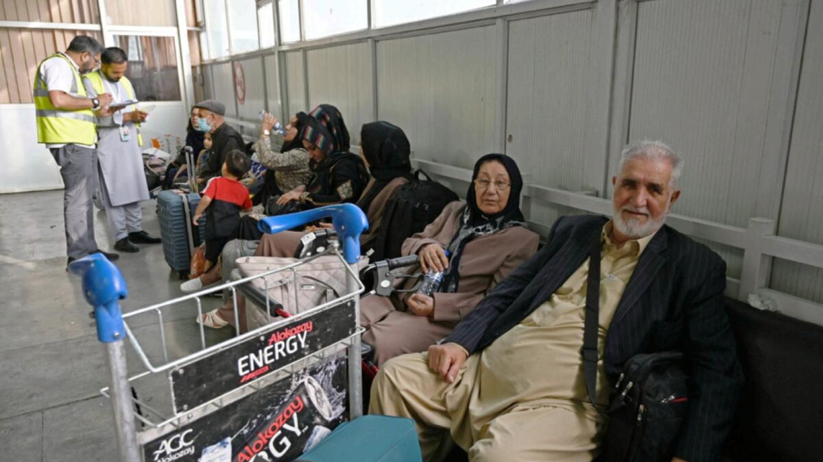 Passengers sit inside the departure terminal before boarding the Qatar Airways flight at the airport in Kabul. — AFP